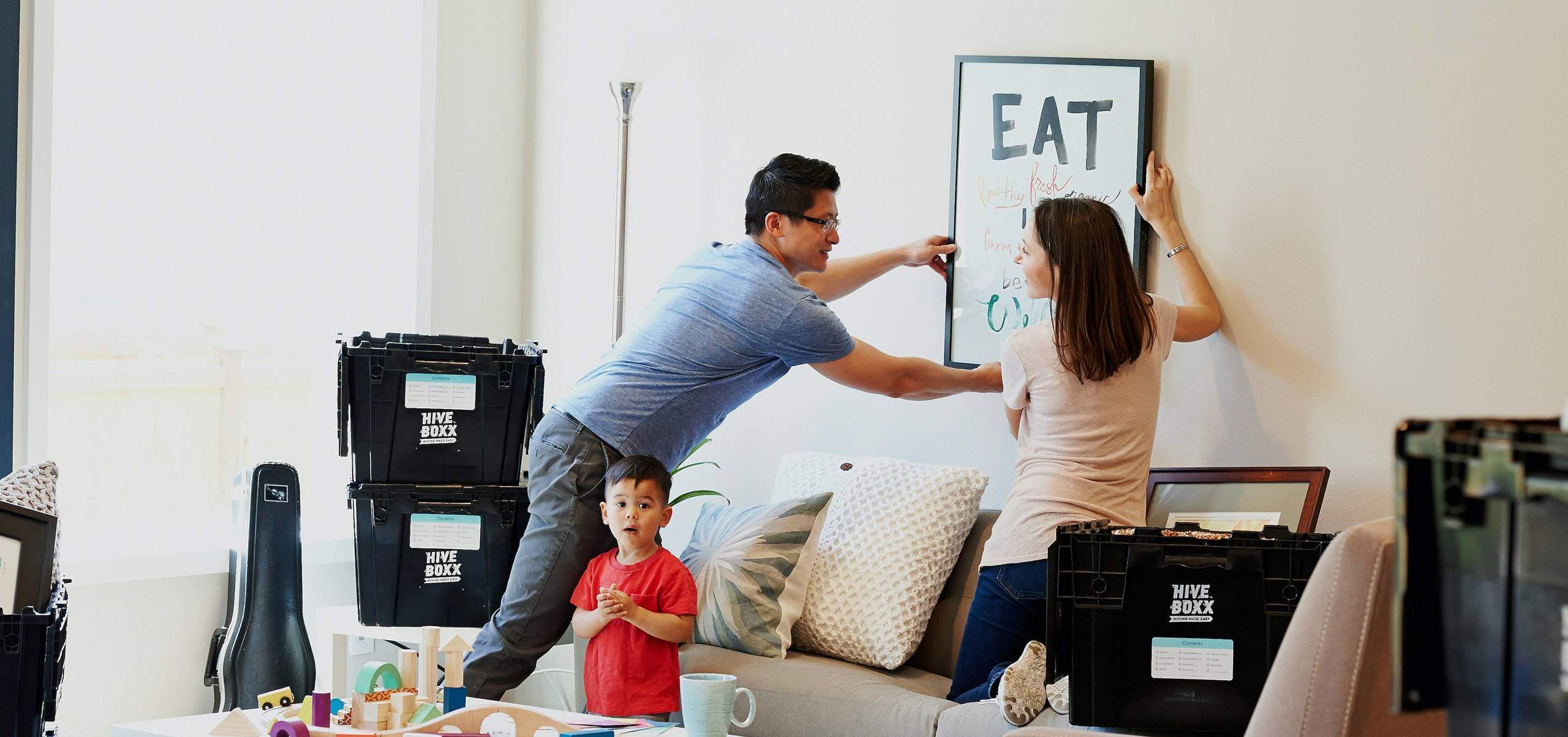 Discover-Hero-image Couple placing an image on the wall with a child standing beside them
